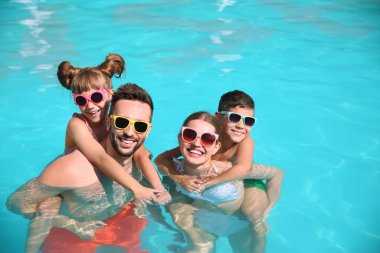 Güneşli bir günde havuzda mutlu bir aile.