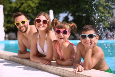 Güneşli bir günde havuzda mutlu bir aile.