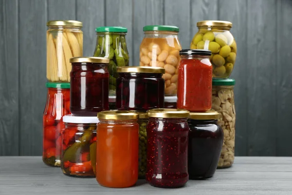 Glazen Potten Met Verschillende Gepekelde Voedingsmiddelen Grijze Houten Ondergrond — Stockfoto