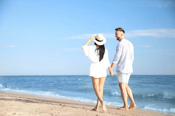 幸せな若いカップルが晴れた日にビーチを歩く — ストック写真