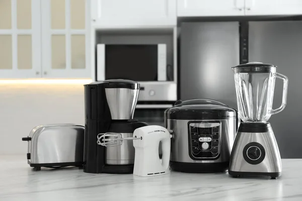 Set of modern home appliances on white marble table in kitchen