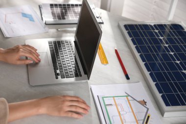 Ofiste güneş panelleri olan ev projesinde çalışan bir kadın, yakın plan.