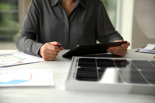 Woman working on project with solar panels at table in office, closeup