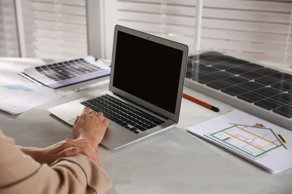 Woman working on house project with solar panels at table in office, closeup