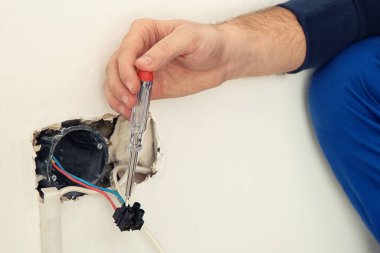 Neon lambalı elektrikçi içeride voltajı kontrol ediyor, yakın plan. 