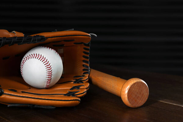 Кожаный бейсбольный мяч, бита и перчатка на деревянном столе
