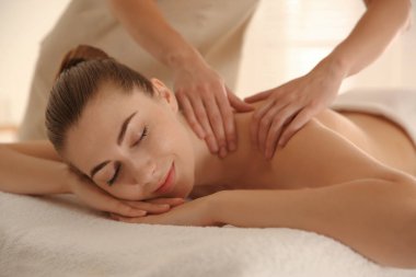 Genç bir kadın spa salonunda omuz masajı yaptırıyor.