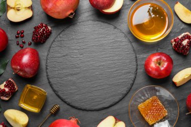 Bal, elma ve nar çerçevesi siyah masanın üzerinde, düzlük ve metin için boşluk. Rosh Hashanah tatili