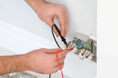 Elektrikçi ve testçi içeride voltajı kontrol ediyor, yakın plan.