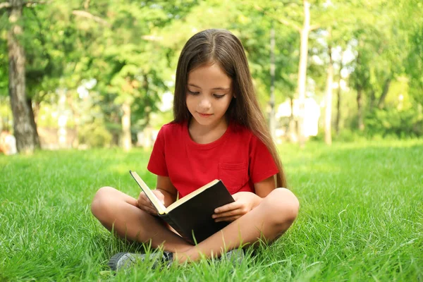 Cute Little Girl Czytania Książki Zielonej Trawie Parku — Zdjęcie stockowe