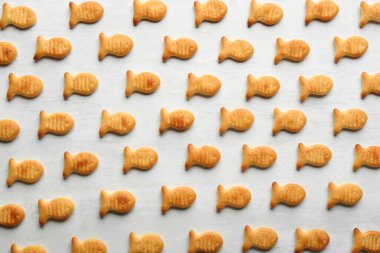 Lezzetli akvaryum balığı krakerleri beyaz masada, düz yerde.