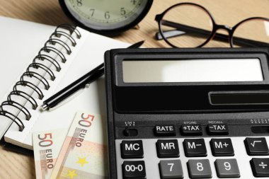 Hesap makinesi, para ve kırtasiye malzemeleri masada, yakın plan. Vergi muhasebesi