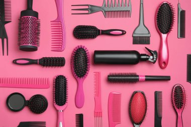 Pembe arka planda modern saç tarakları ve fırçalarla düz kompozisyon