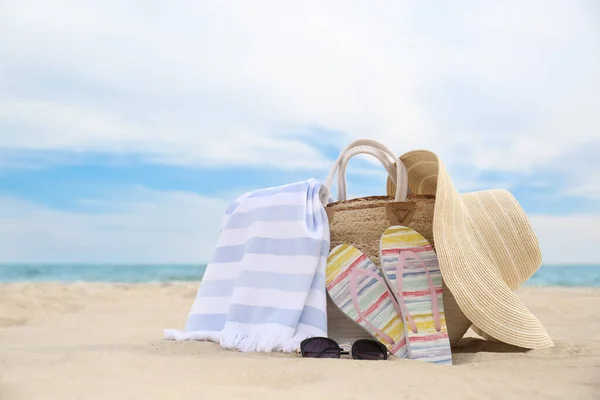Different stylish beach objects on sand near sea