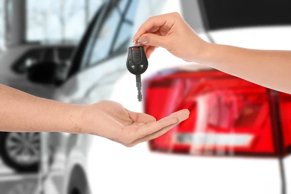 車の購入 ぼやけた自動車に対して新しい所有者に鍵を与える女性 クローズアップ — ストック写真