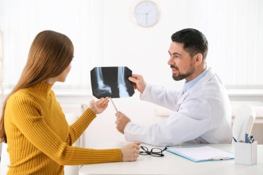 Ortopedist, klinikteki hastaya röntgen filmi gösteriyor.