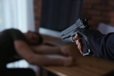 Silahlı bir adam ve kurbanı odada, yakın plan. Tehlikeli suçlu.