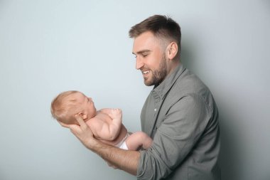 Açık gri arka planda yeni doğmuş oğlu olan baba.