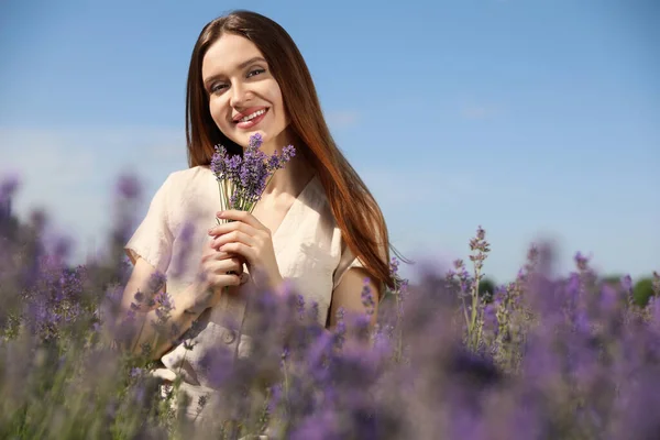 Young woman with lavender bouquet in field on summer day