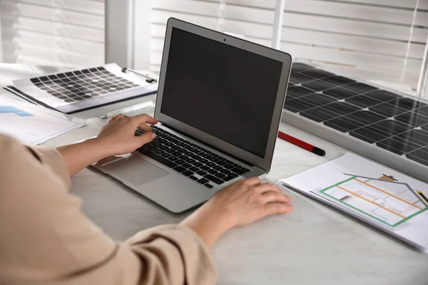 Woman working on house project with solar panels at table in office, closeup