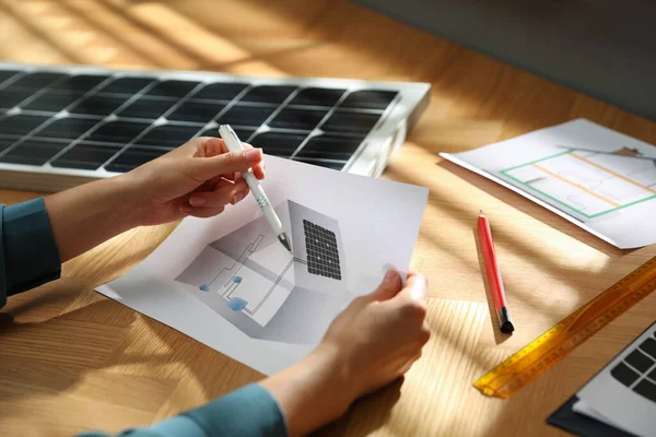 Woman working on house project with solar panels at table in office, closeup