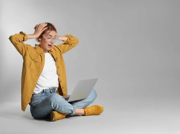 Giovane Donna Emotiva Con Computer Portatile Sfondo Grigio Spazio Testo — Foto Stock