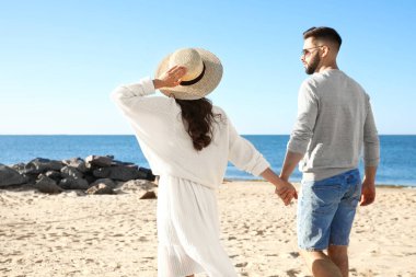 Deniz kenarında yürüyen mutlu genç bir çift. Balayı gezisi