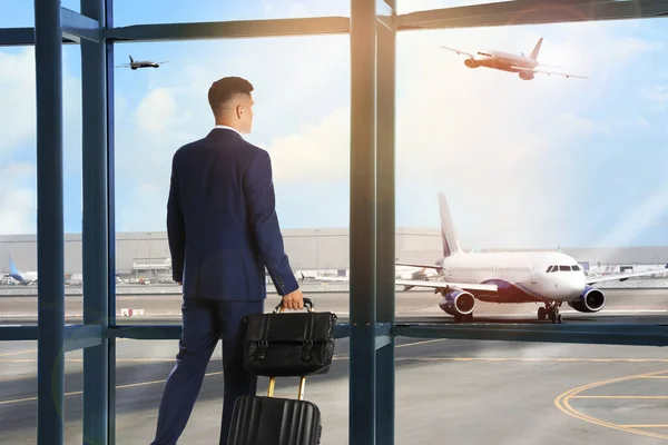 Businessman with bag and travel suitcase at airport terminal. Summer vacation