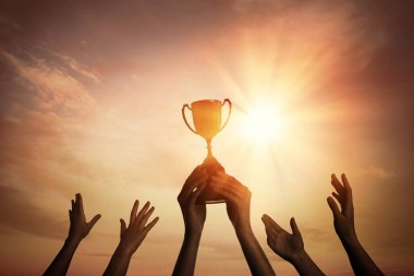 Gökyüzünde parlayan güneşe karşı altın kupa ile kazanan takım 