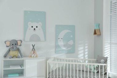 Şık bir bebek odası, içinde beşik ve duvarında sevimli resimler var.
