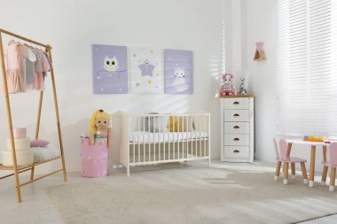 Bebek odasının içinde şirin posterler, karyola ve elbise rafları var.