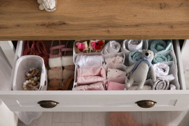 Bebek kıyafetleri ve aksesuarları olan modern açık çekmeceler.