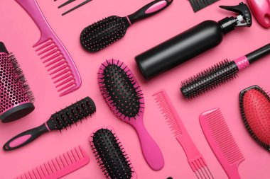 Pembe arka planda modern saç tarakları ve fırçalarla düz kompozisyon