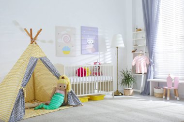 Bebek odasının içinde sevimli posterler, çadır ve rahat bir beşik var.