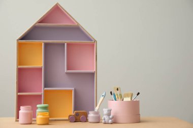 Ev şekilli raflı kompozisyon ve masada kavanozlar dolusu boya, yazı için boşluk. İç öge