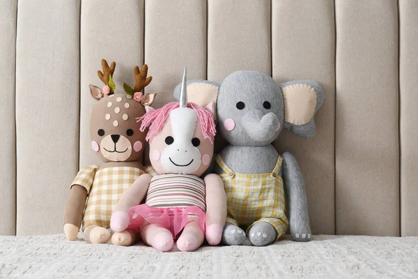 Funny toy unicorn, deer and elephant on bed. Decor for children's room interior