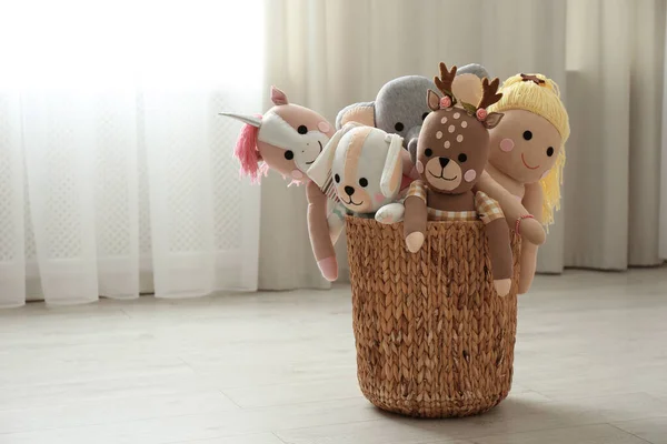 Funny stuffed toys in basket on floor, space for text. Children\'s room interior decor