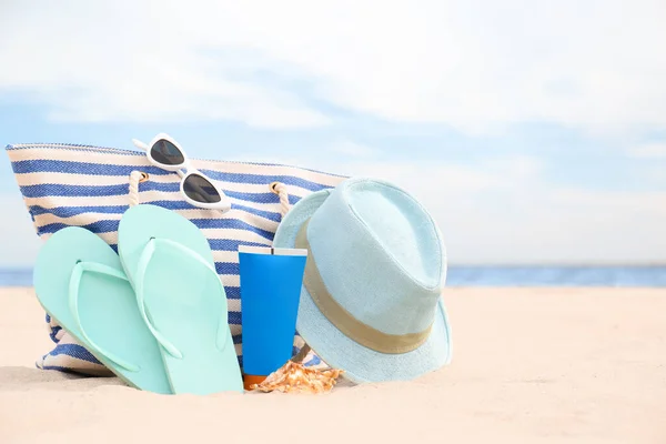 Different stylish beach objects on sand near sea