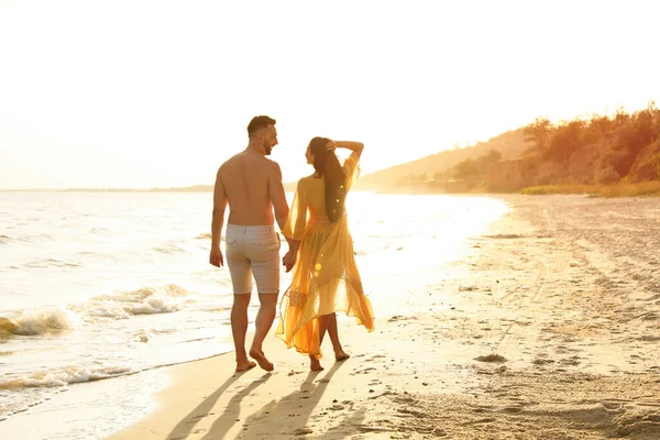 夕阳西下 一对快乐的情侣在沙滩上散步 回头看 — 图库照片