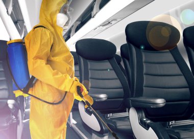 Coronavirus 'un yayılmasını önlemek için uçakta koruyucu elbise giyen bir adam.