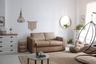 Modern oturma odasındaki şık deri kanepe ve salıncaklı sandalye.