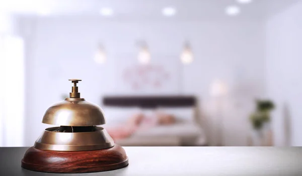 Grey table with hotel service bell and blurred room on background. Space for text