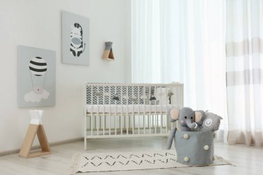 Şık bir bebek odası, içinde beşik ve duvarında sevimli resimler var.