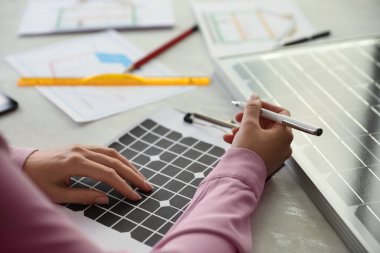 Ofisteki masada güneş panelleriyle projede çalışan kadın, yakın plan.