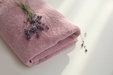 Beyaz masada katlanmış temiz havlu ve lavanta çiçekleri, yakın plan.