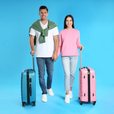 Mavi arka planda yaz gezisi için bavulları olan mutlu çift. Tatil gezisi