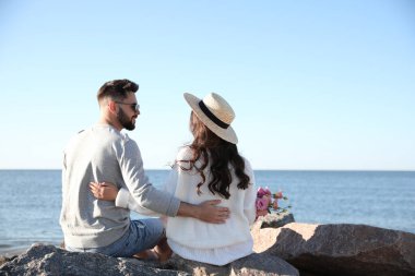 Kumsalda çiçekleri olan mutlu genç bir çift. Balayı gezisi