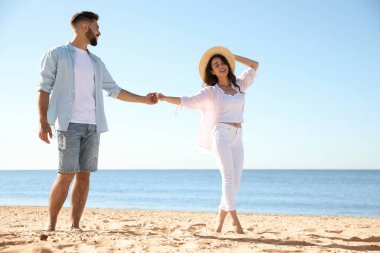 Deniz kenarında yürüyen mutlu genç bir çift. Balayı gezisi