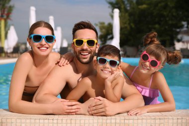 Güneşli bir günde havuzda mutlu bir aile.