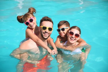 Güneşli bir günde havuzda mutlu bir aile.